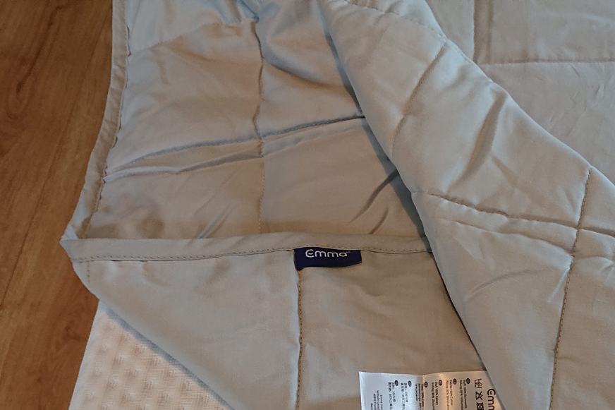 Cobertor pesado marca Emma com dobra para mostrar a camada de poliéster